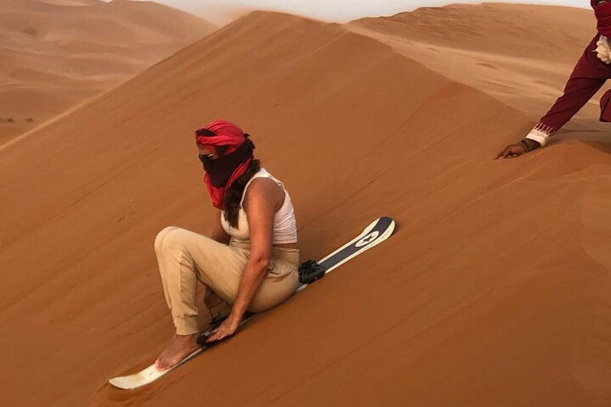 una donna seduta su una duna di sabbia nel deserto