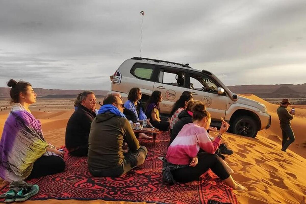 a group of people sitting in front of a truck in the desert