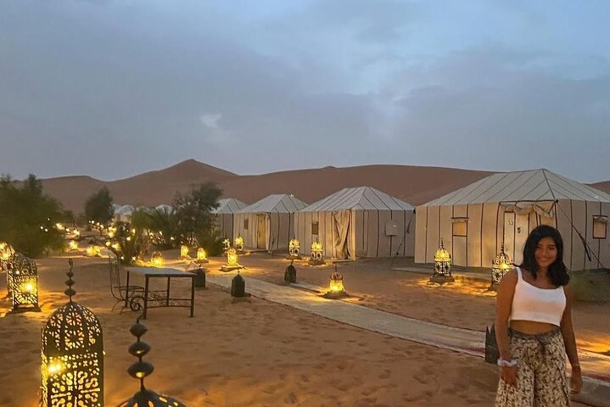 a woman standing in front of tents in the desert