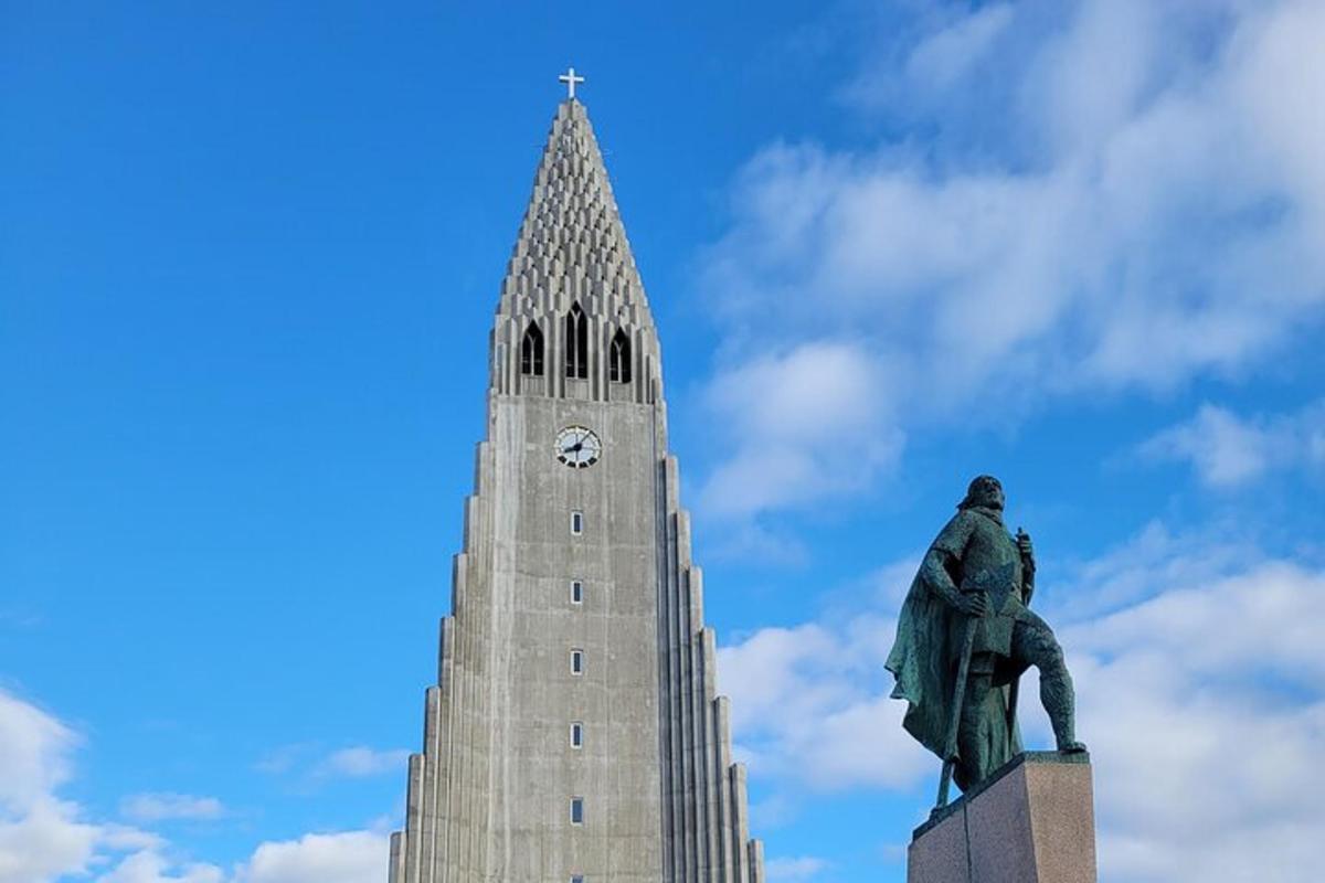 una statua di fronte a un edificio con una torre dell'orologio