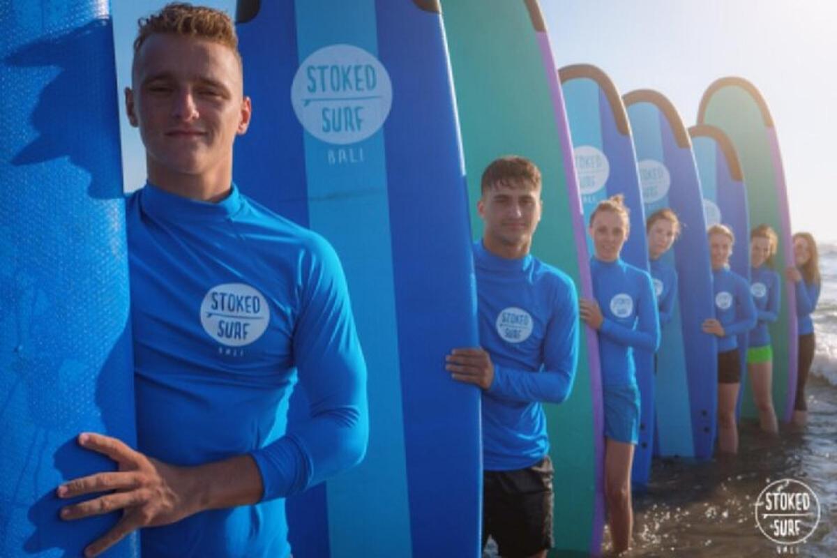 Un grupo de hombres de pie frente a tablas de surf.