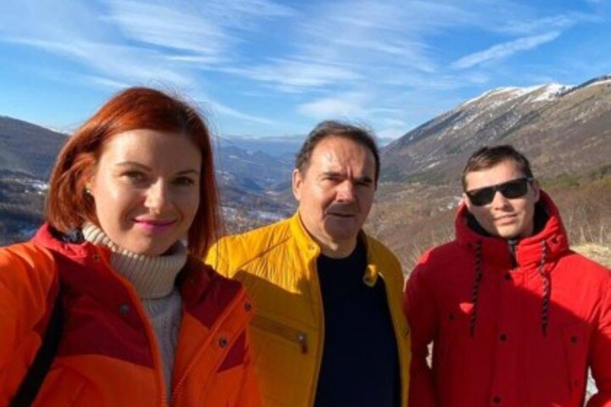 Dos hombres y una mujer de pie en la cima de una montaña