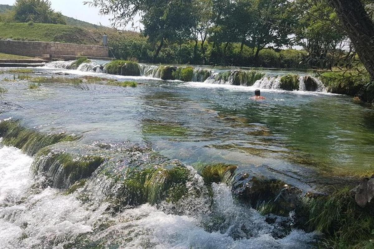 osoba plavající v řece s vodopádem