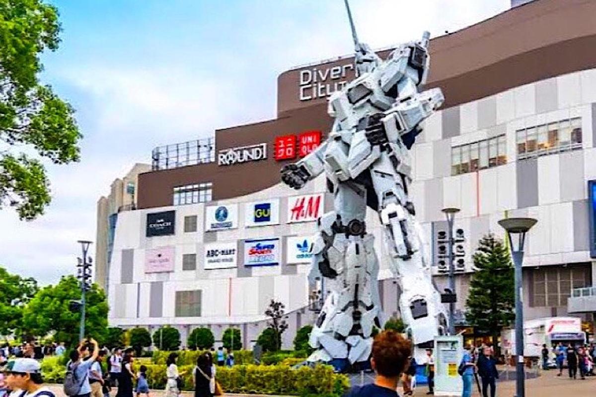 Un hombre parado frente a un edificio con una estatua de robot.