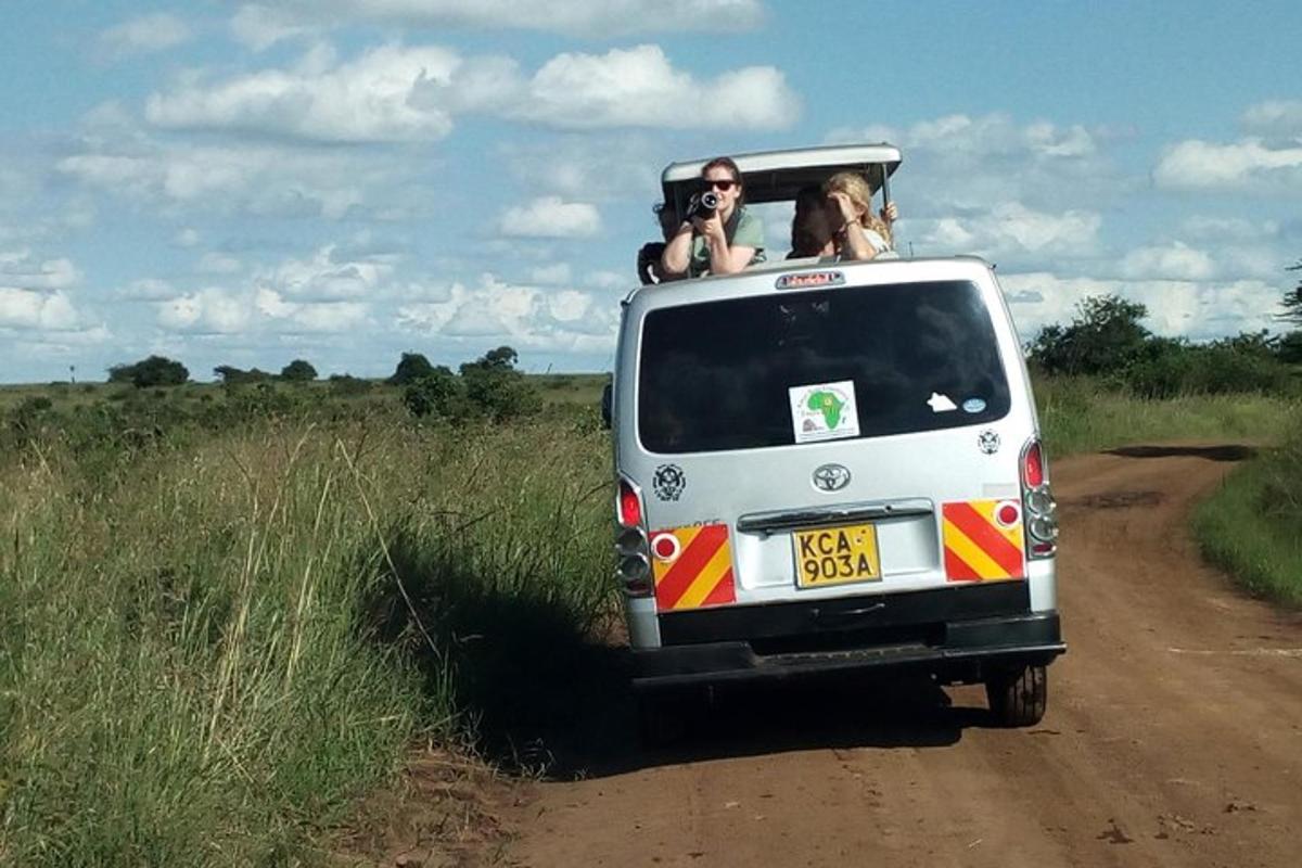 two people in the back of a vehicle on a dirt road