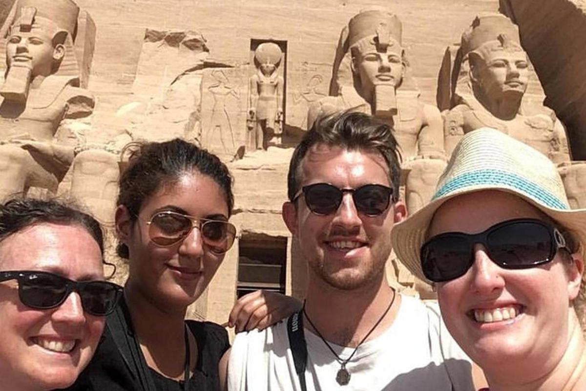 tre persone sono in piedi davanti a una statua