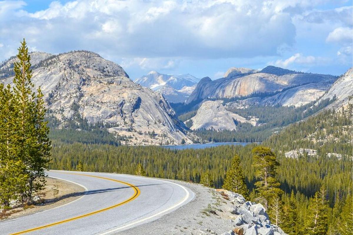 a winding road with mountains and a lake in the distance