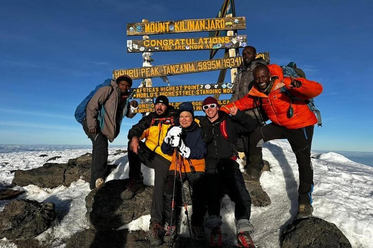 en gruppe mennesker som står foran et skilt på et fjell