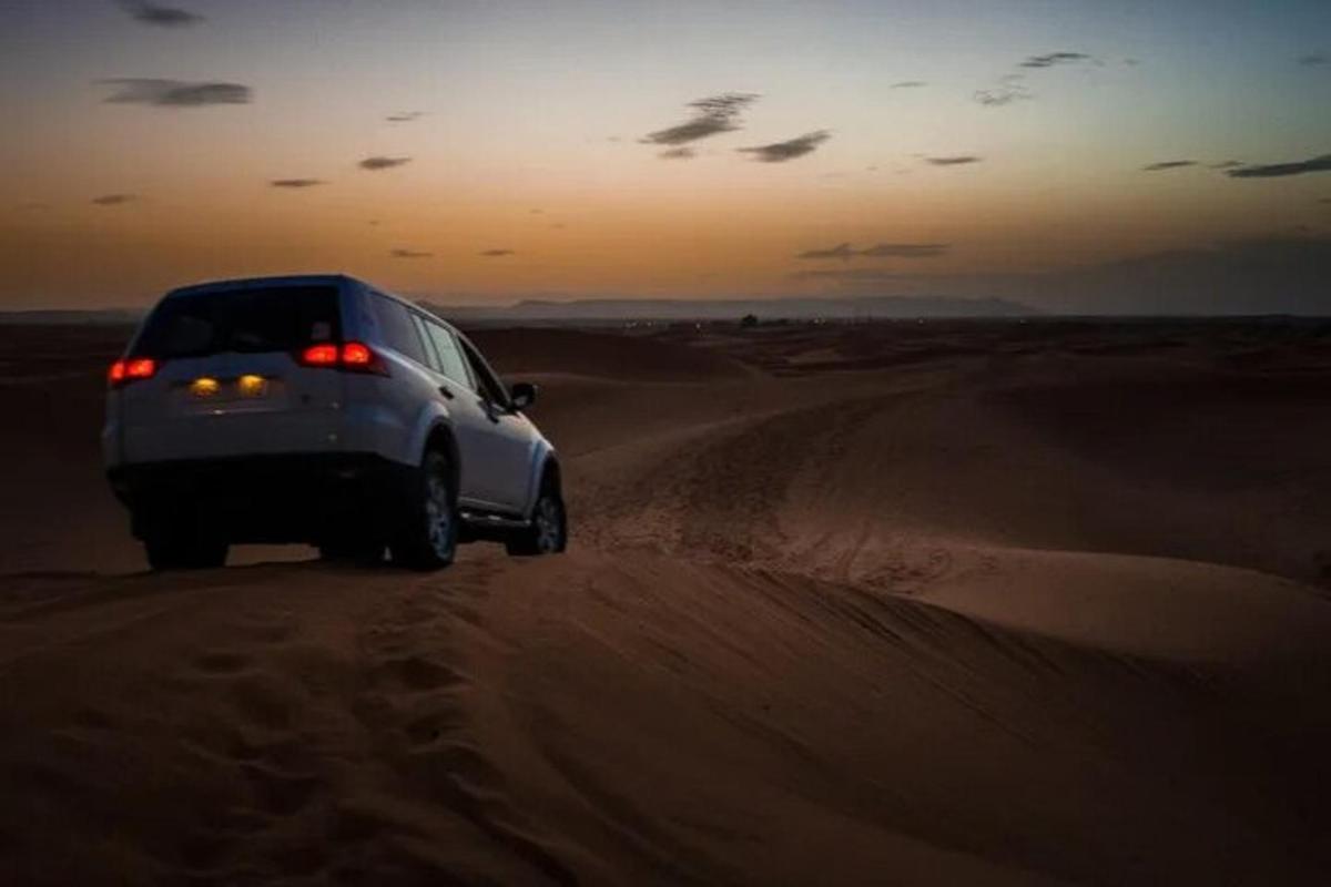 un cotxe circulant per la sorra del desert