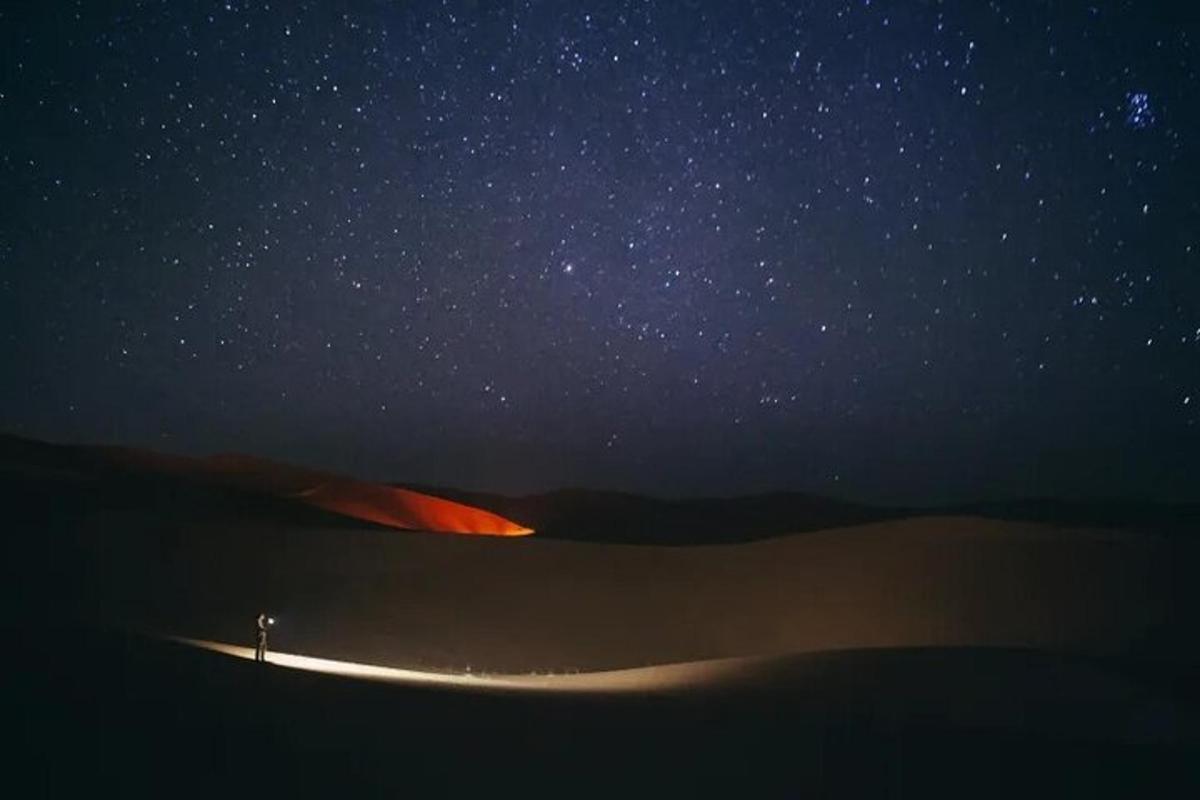una persona dempeus al desert sota un cel estrellat