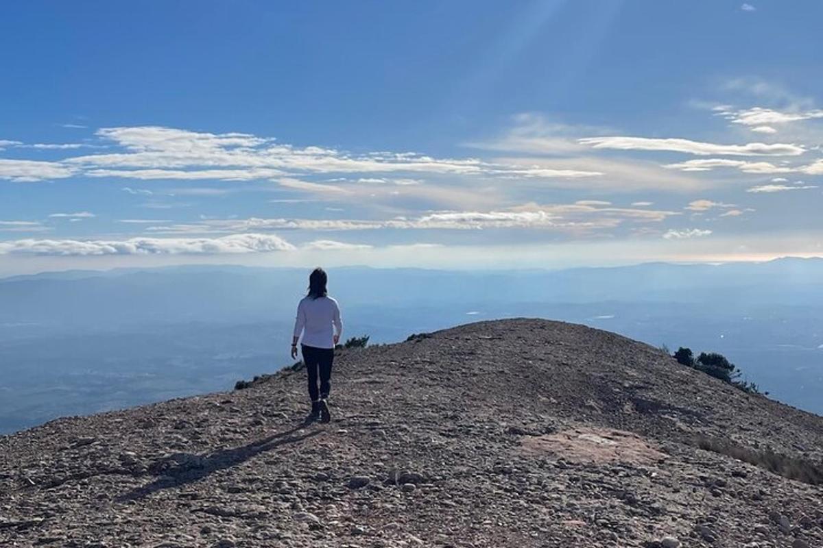 una donna in piedi sulla cima di una montagna che domina l'oceano
