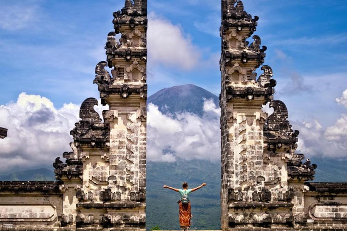 seorang wanita berdiri di antara dua menara dengan latar belakang gunung