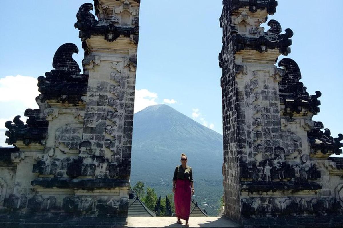 seorang wanita berdiri di antara dua menara dengan latar belakang gunung