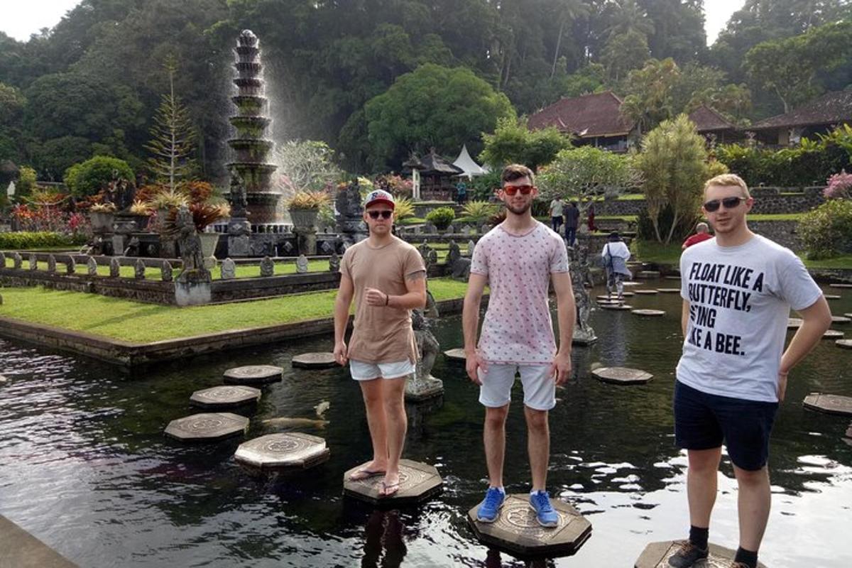 tiga lelaki berdiri di atas batu loncatan di dalam kolam