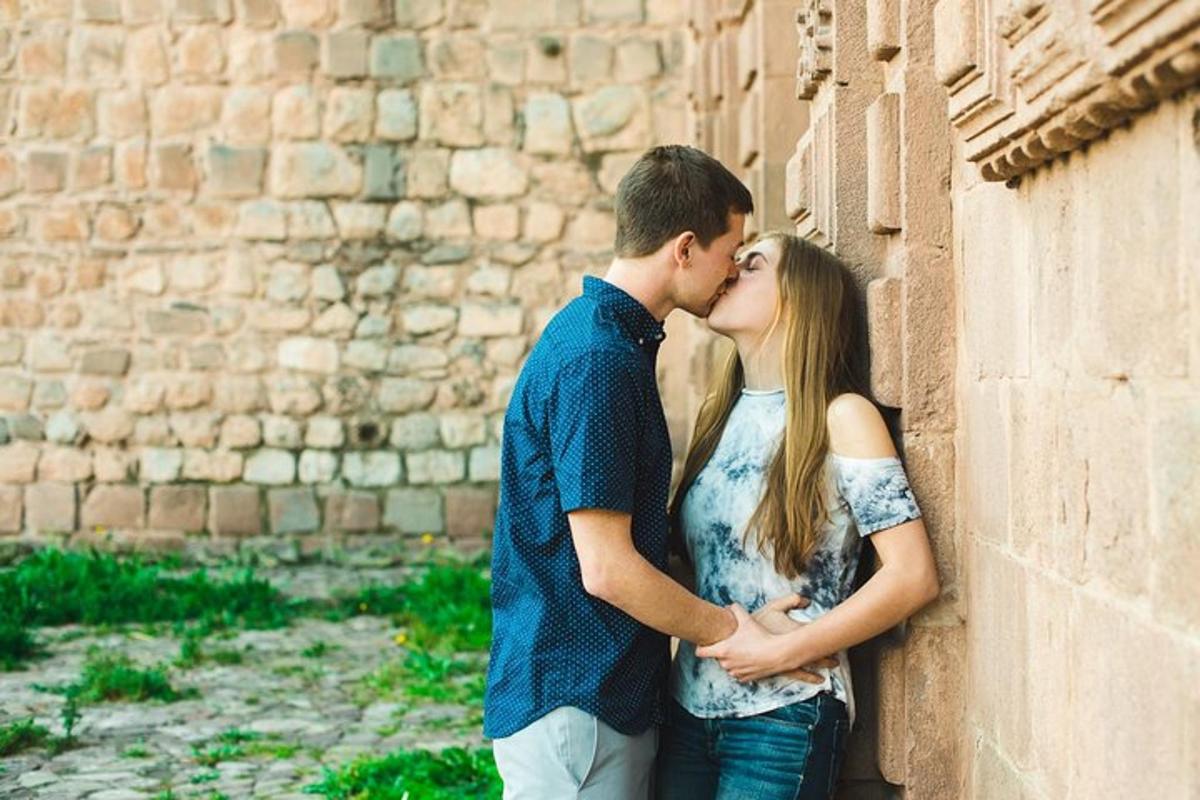 un uomo e una donna che si baciano contro un muro