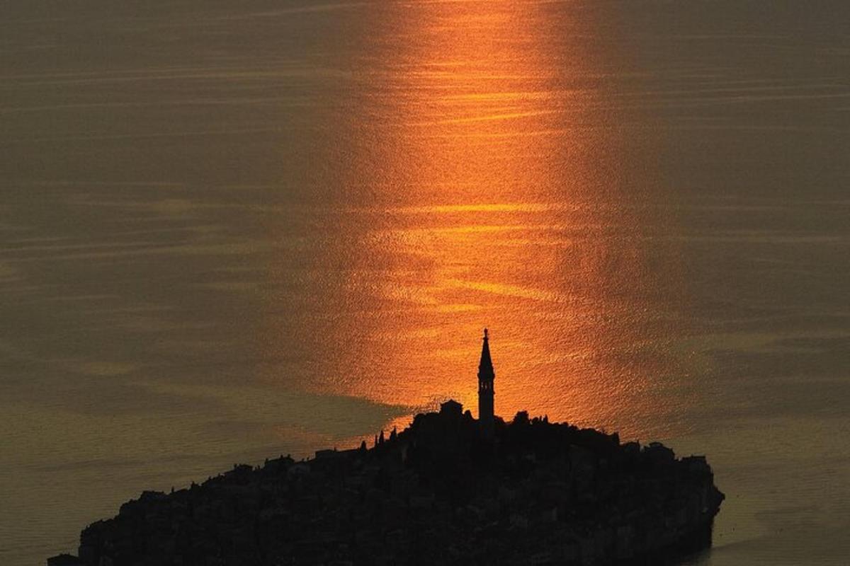 um farol em uma ilha no oceano ao pôr do sol
