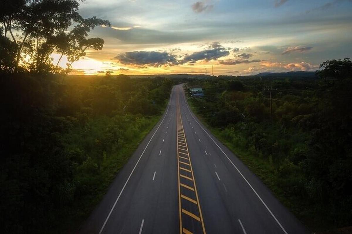 jalan raya kosong dengan matahari terbenam di latar belakang