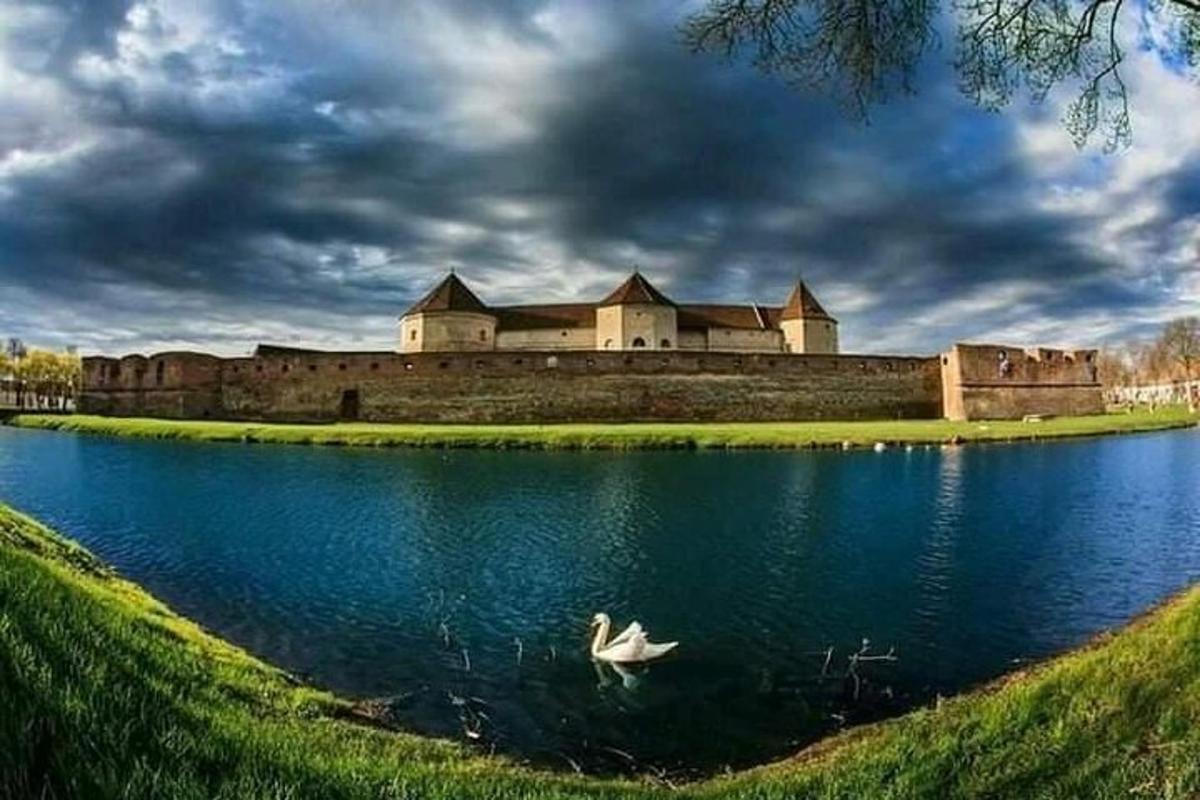 a white boat in the water in front of a castle