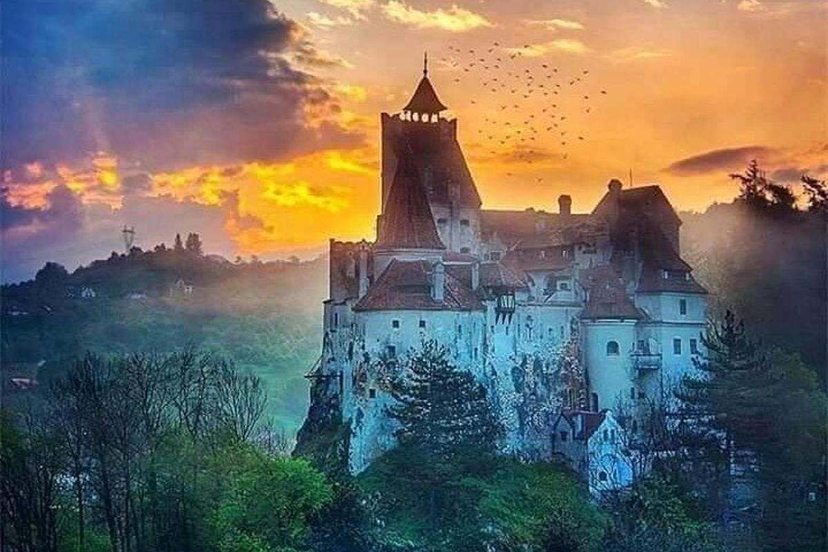 un castel pe un deal cu un apus de soare în fundal