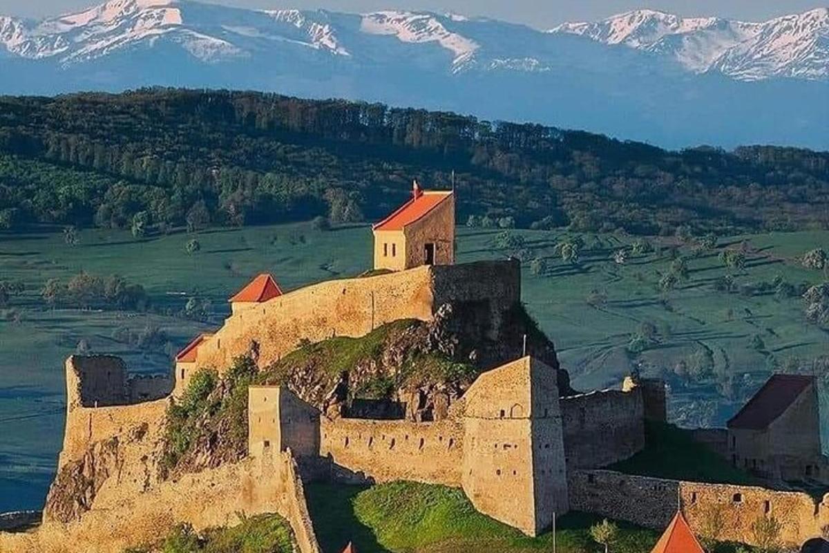 o clădire pe vârful unui deal cu munți acoperiți de zăpadă