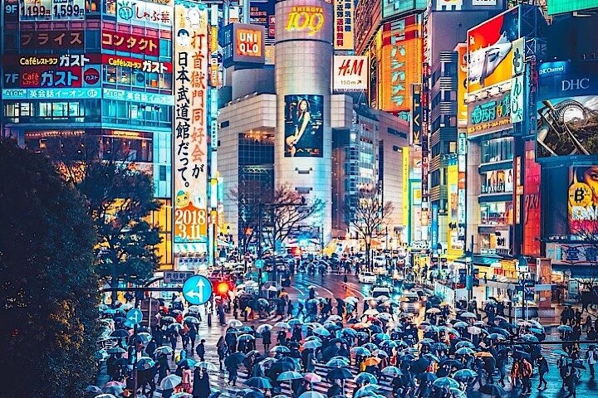una strada cittadina trafficata con una folla di persone con gli ombrelli