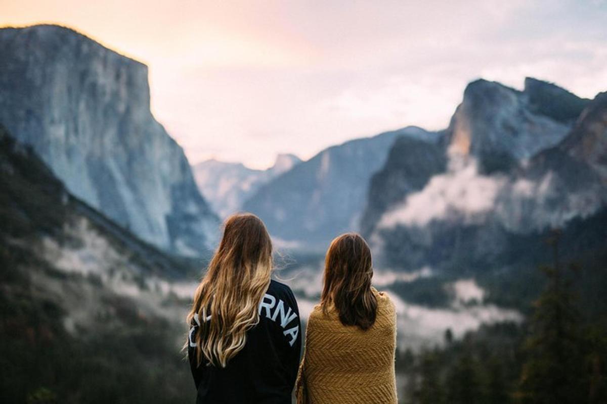Dos mujeres de pie en la cima de una montaña mirando las montañas