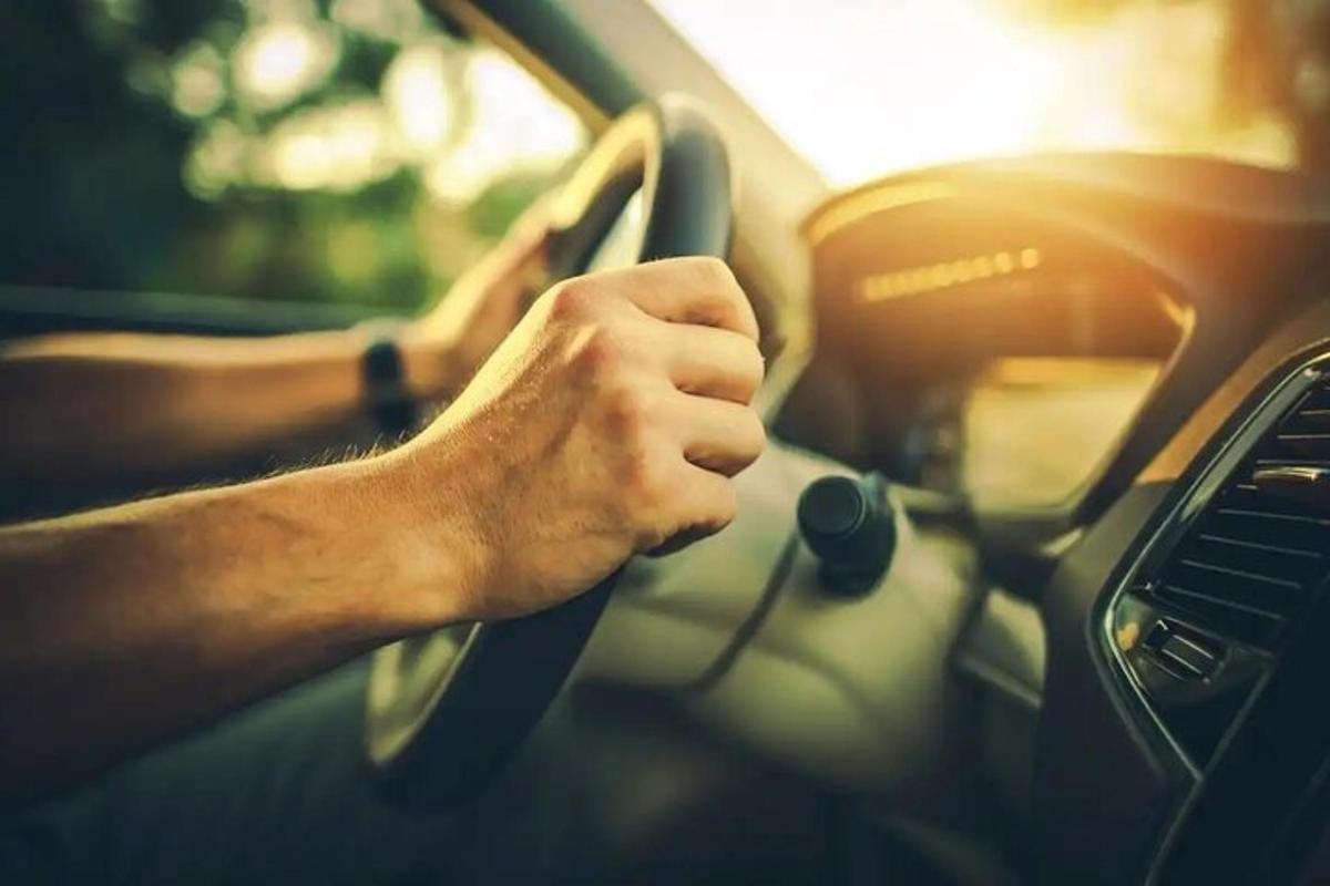muž řídící auto s rukama na volantu