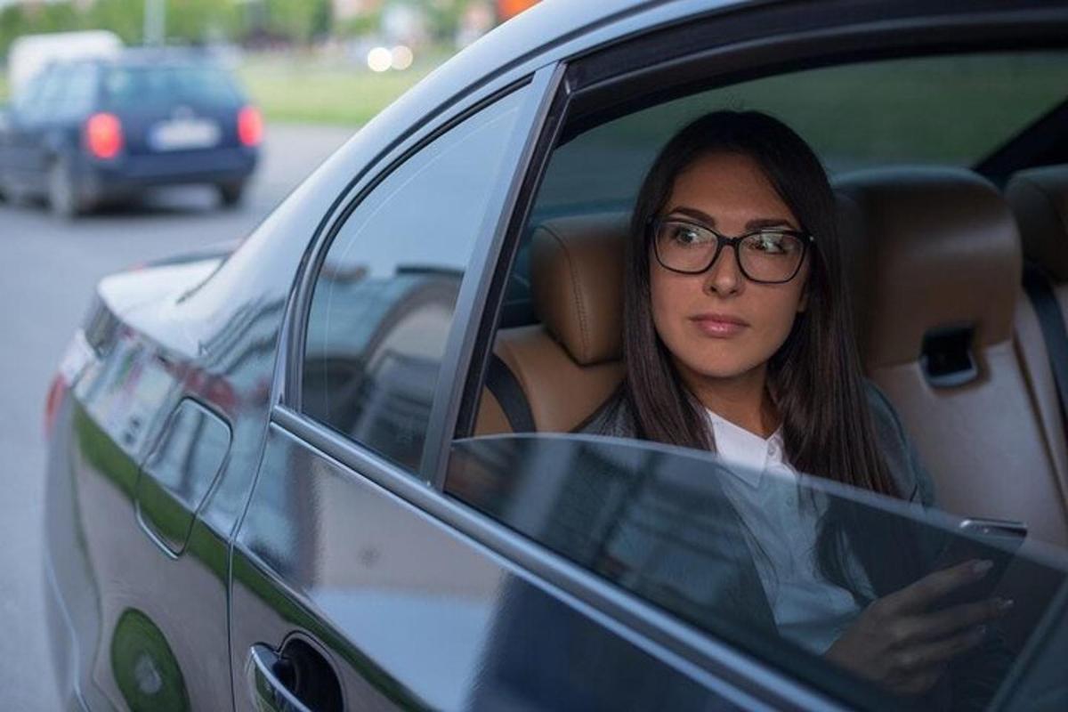 žena sedící v autě a dívající se do svého mobilního telefonu
