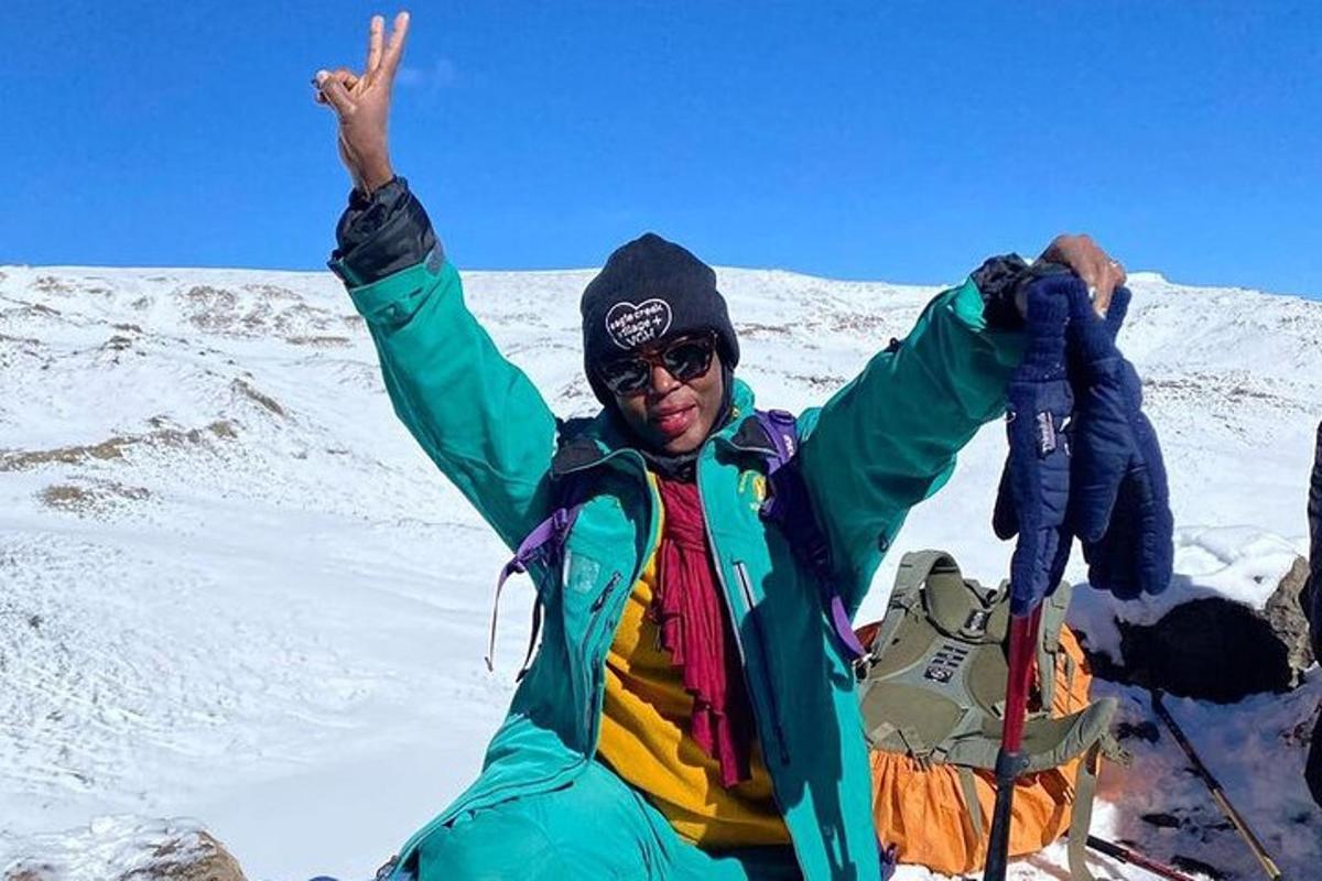 seorang pria berdiri di atas gunung yang tertutup salju