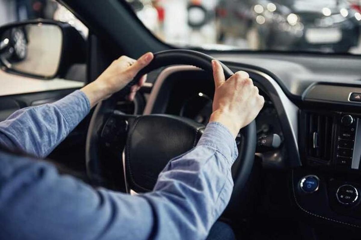 muž řídící auto s rukama na volantu
