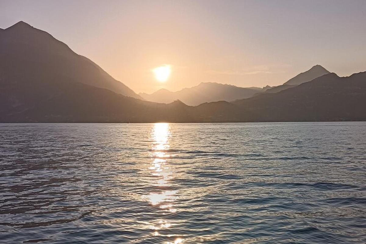 a sunset on the water with mountains in the background