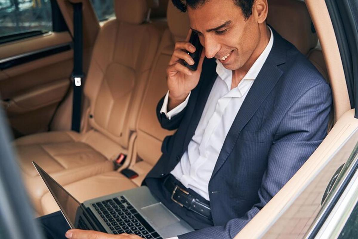 um homem sentado no banco de trás de um carro usando um laptop