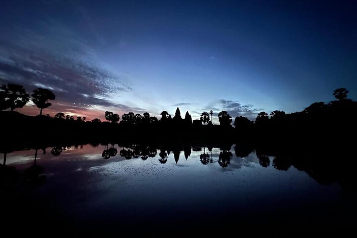 matahari terbenam di atas tasik dengan pokok di latar belakang