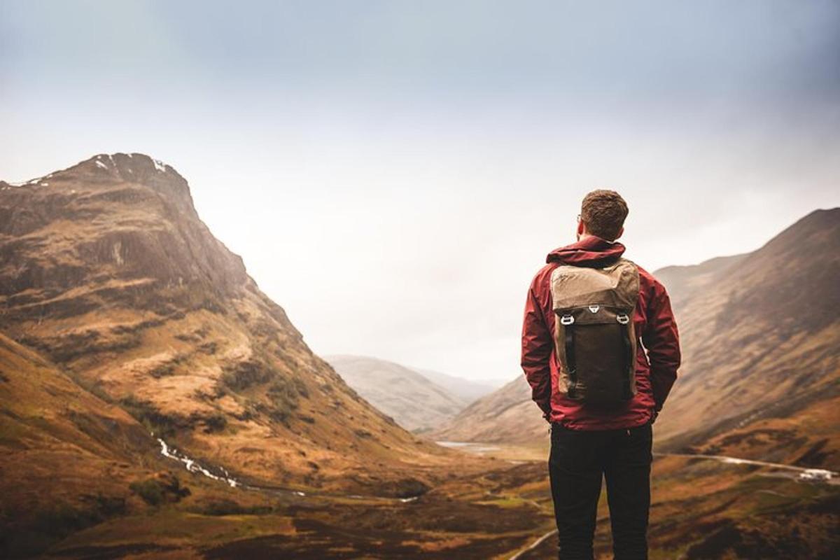 maður stendur á fjallstindi og horfir yfir dalinn