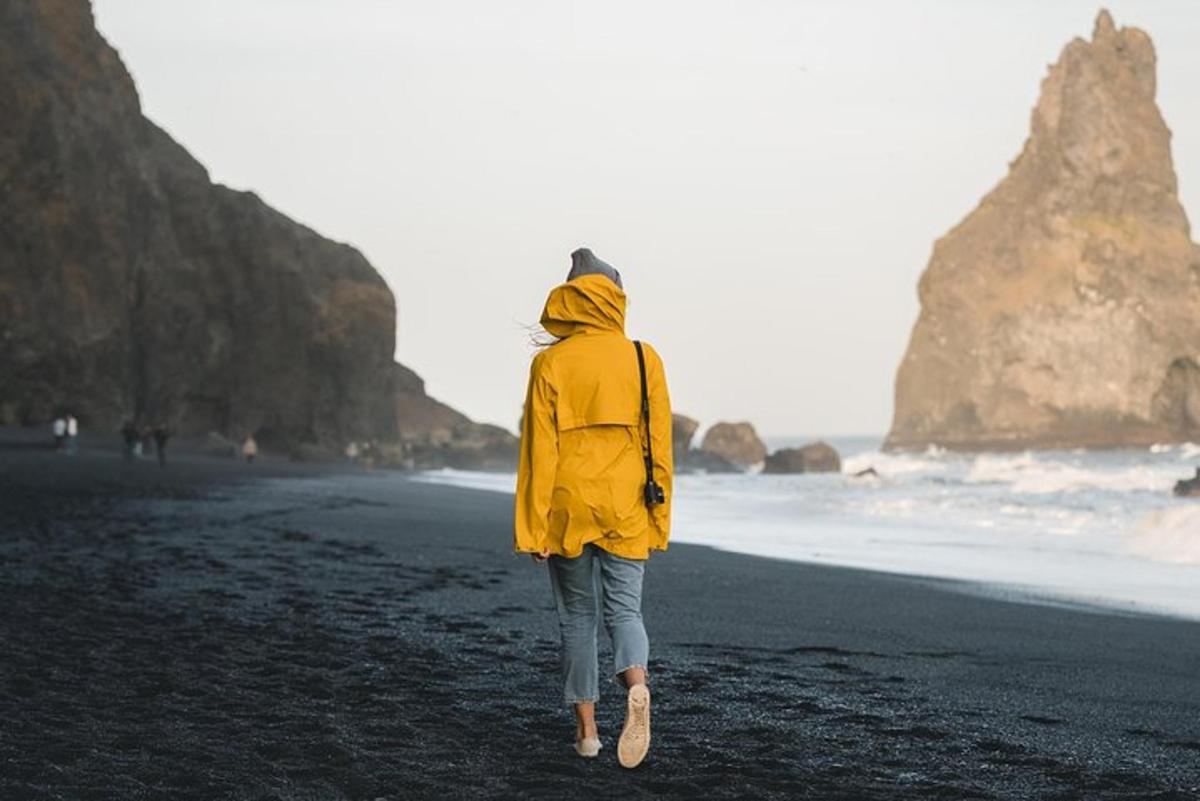 seorang wanita berjalan di pantai dengan jaket kuning