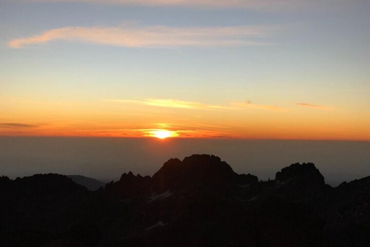 un tramonto sulle montagne con il sole nel cielo