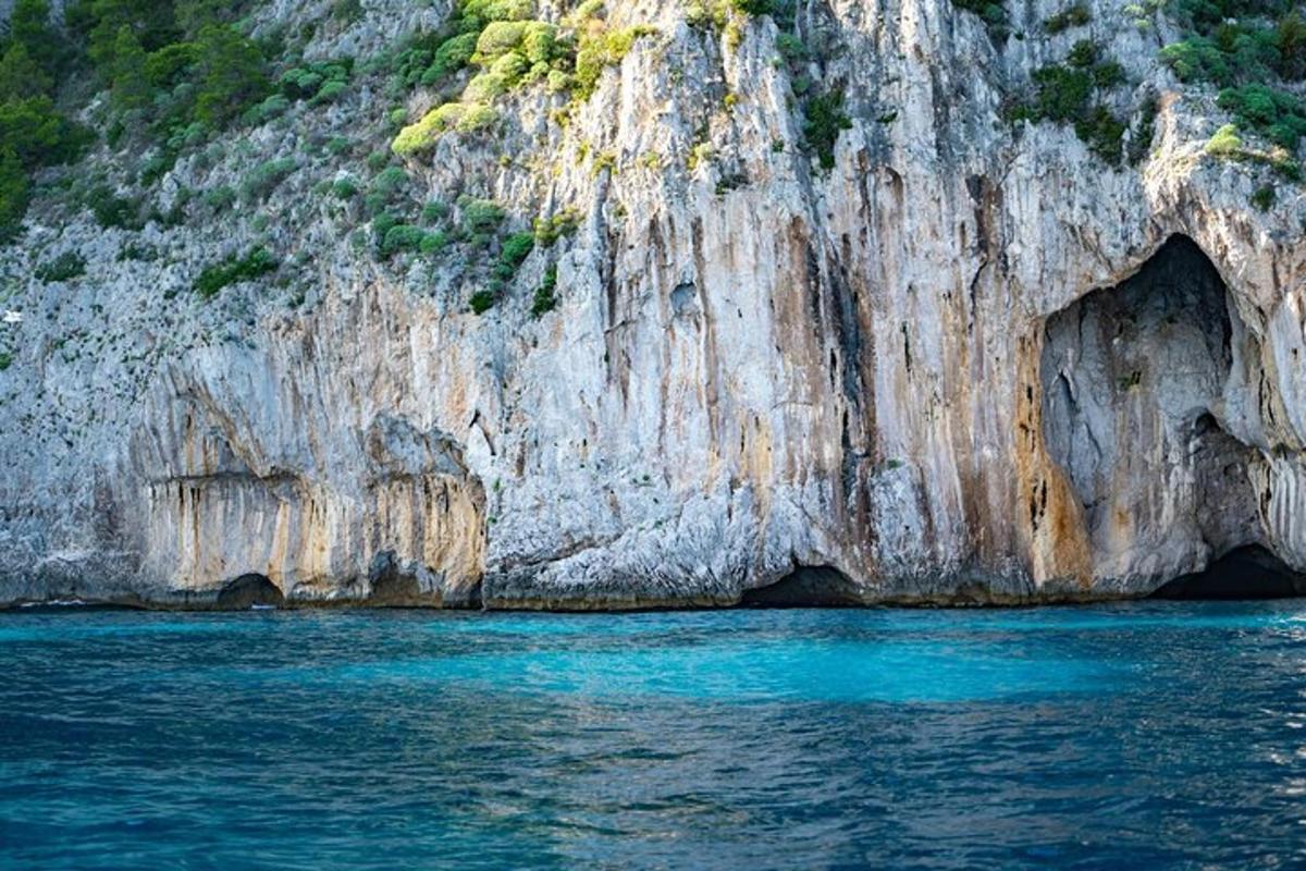 eine große Felsklippe mit blauem Wasser davor