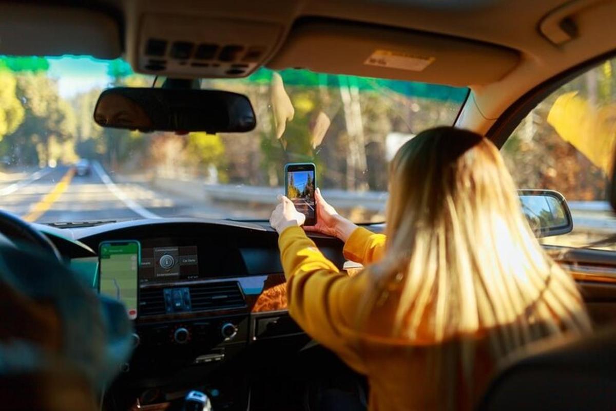 seorang wanita memegang telepon seluler di dalam mobil