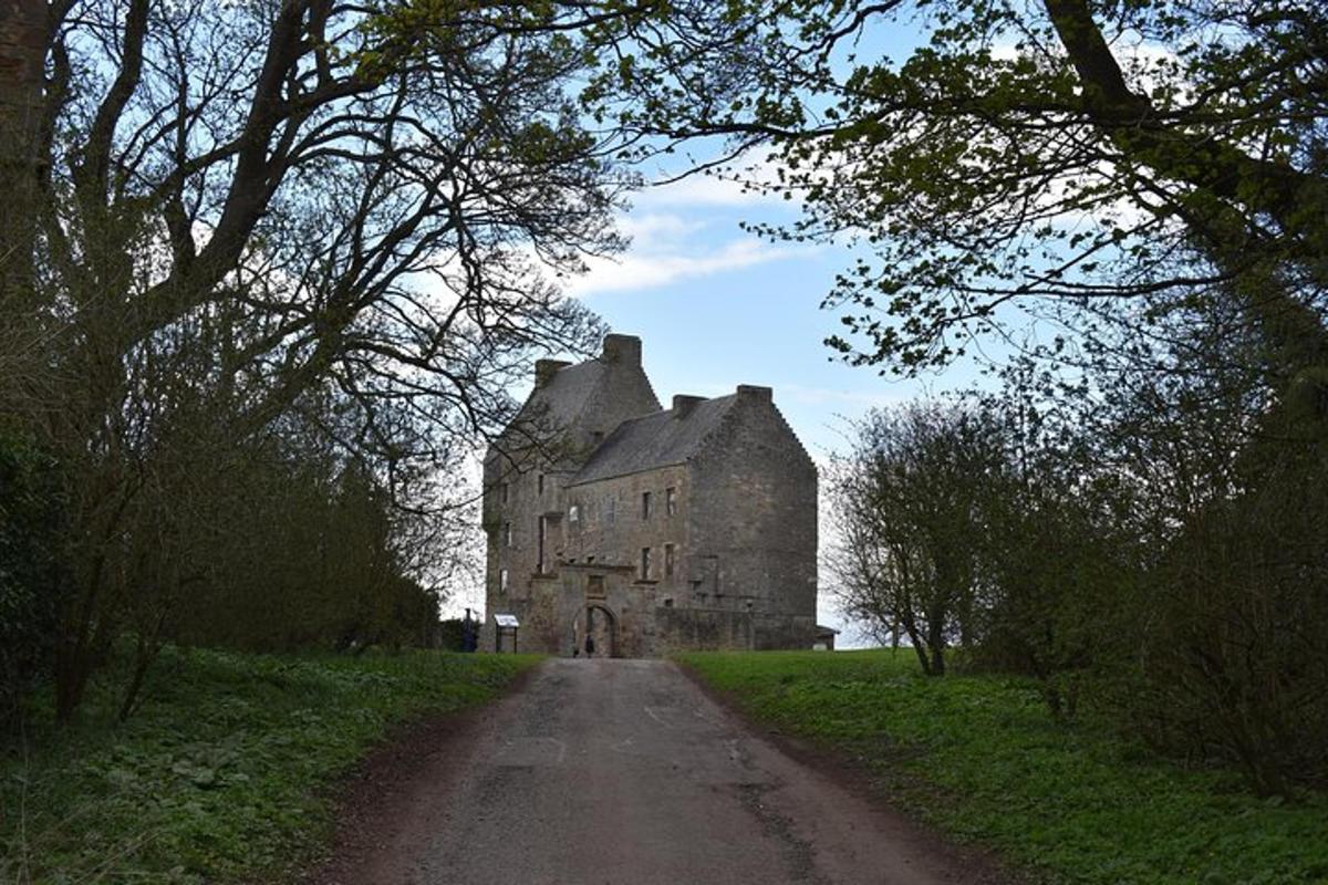 um velho castelo em um campo com uma estrada de terra