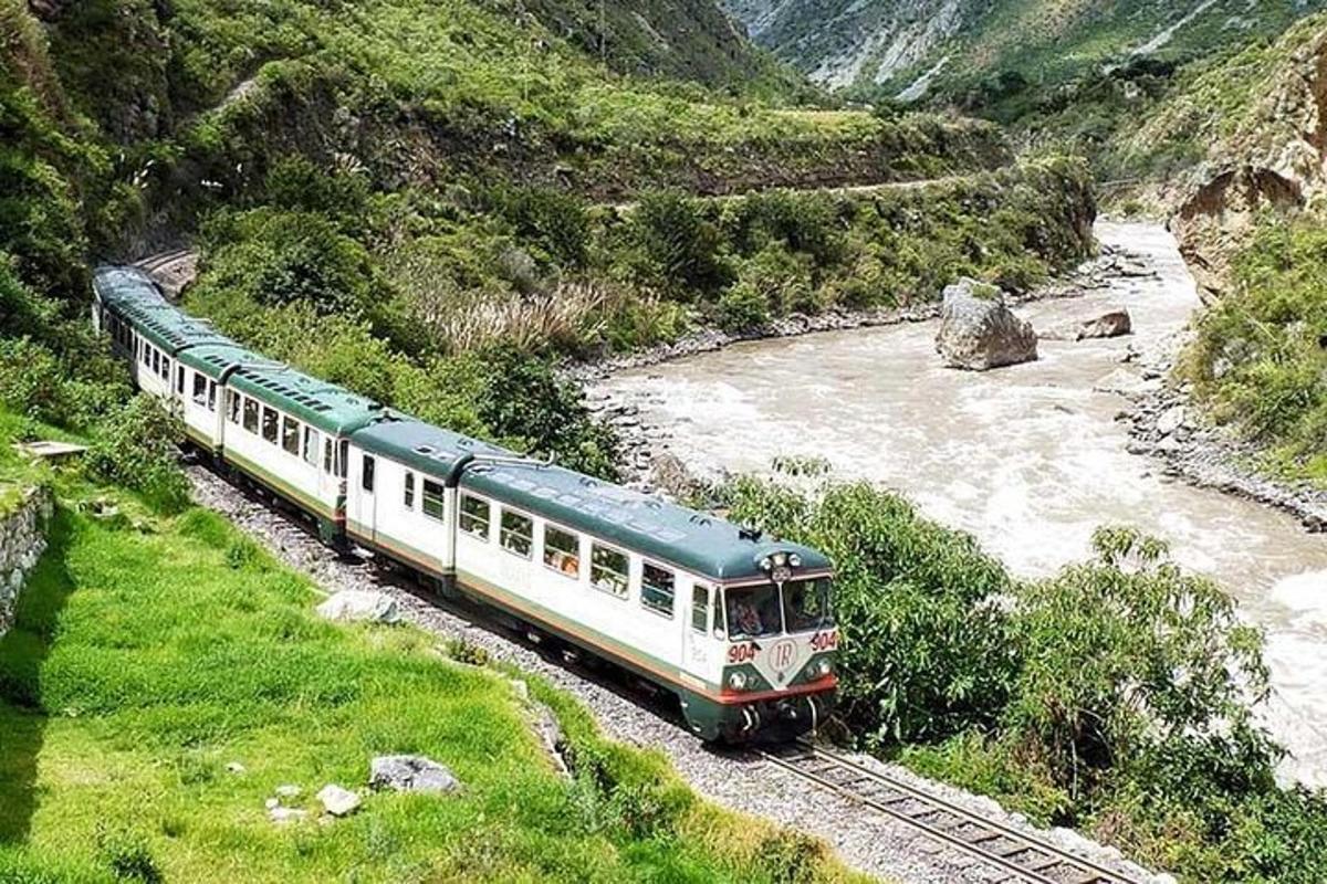 um trem verde e branco nos trilhos ao lado de um rio