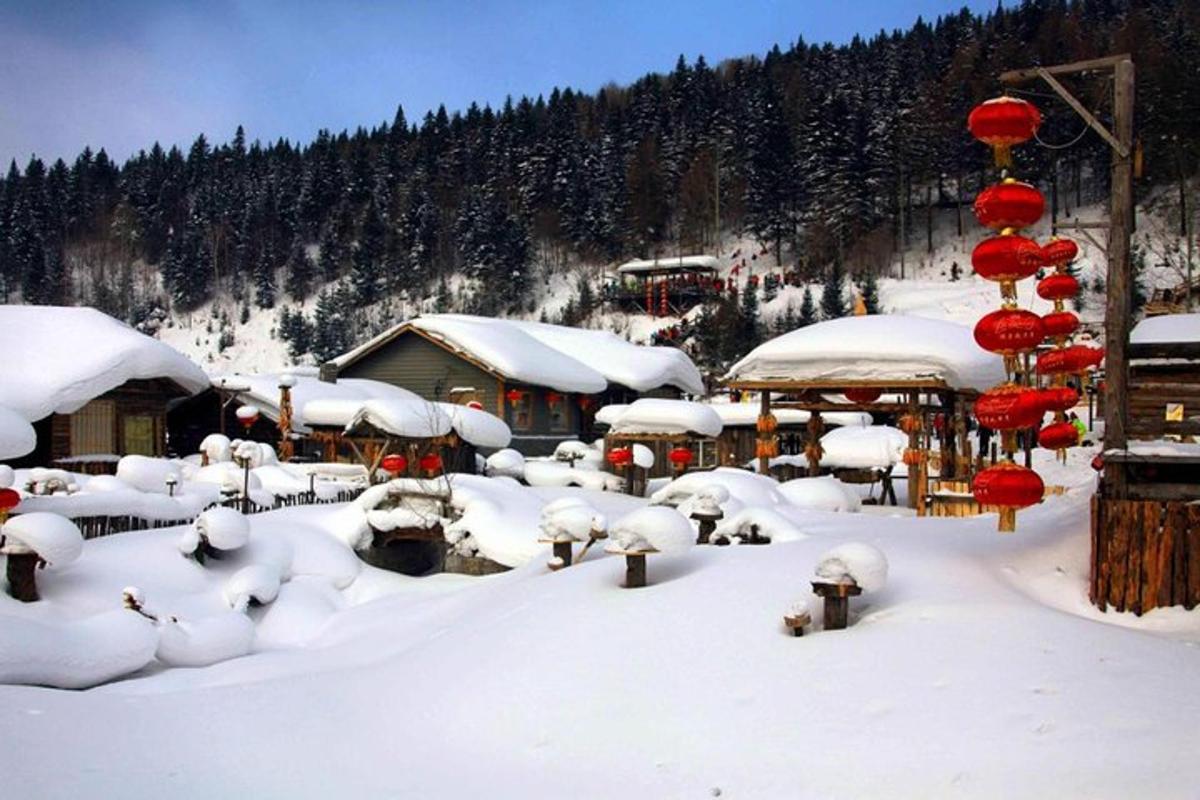 a village covered in snow with red lanterns