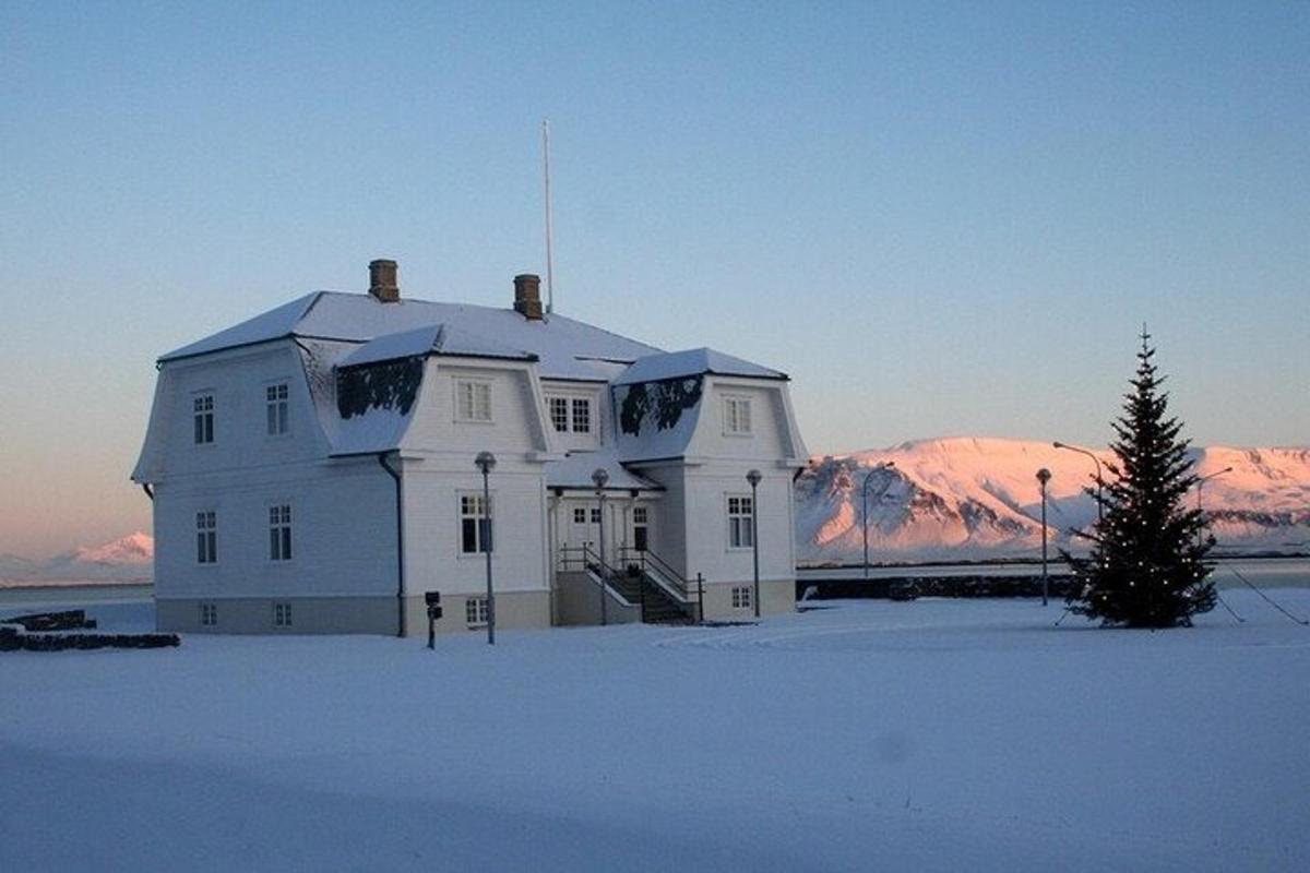 Una casa blanca en la nieve con un árbol de Navidad.