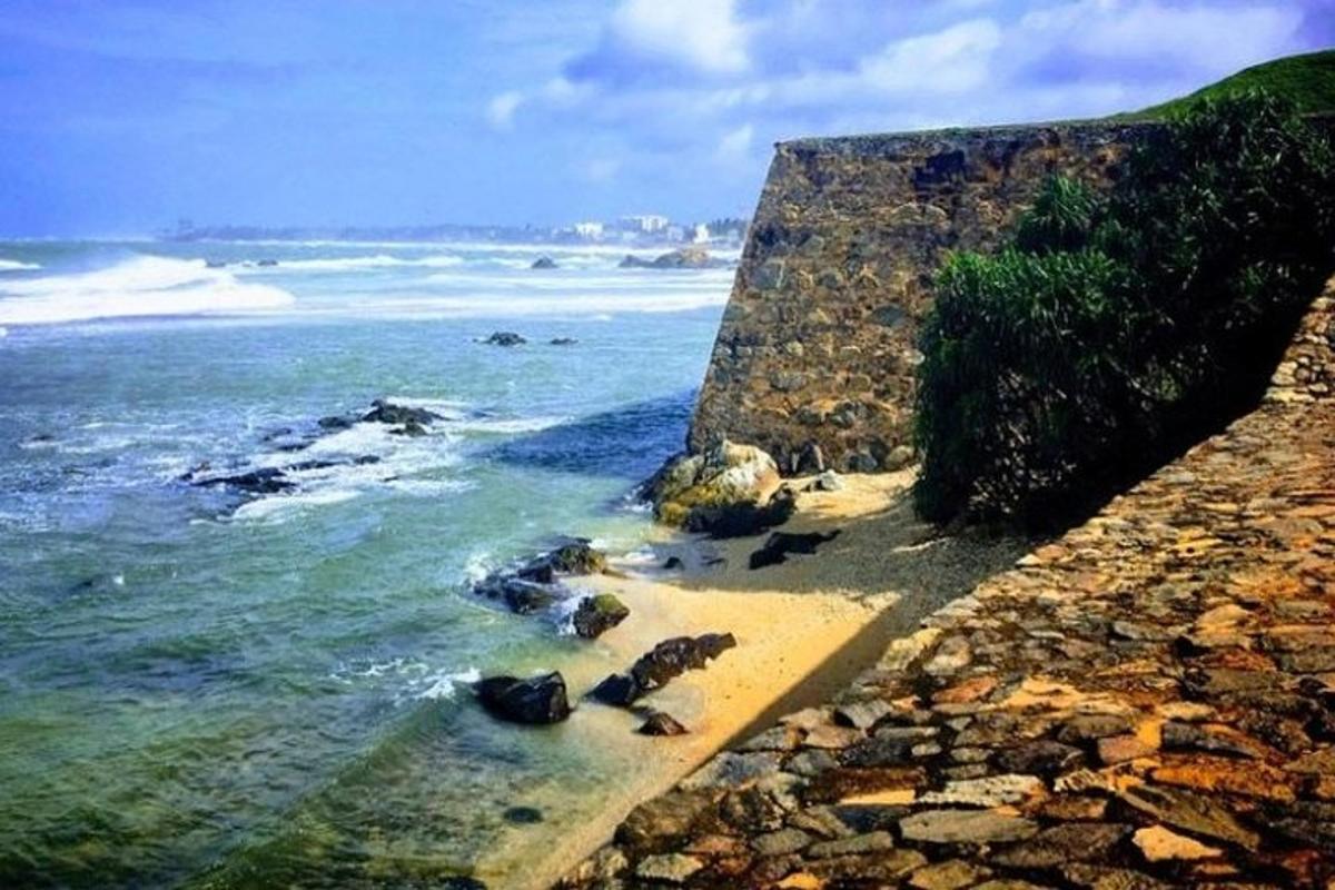 una spiaggia con rocce, l'oceano e un muro