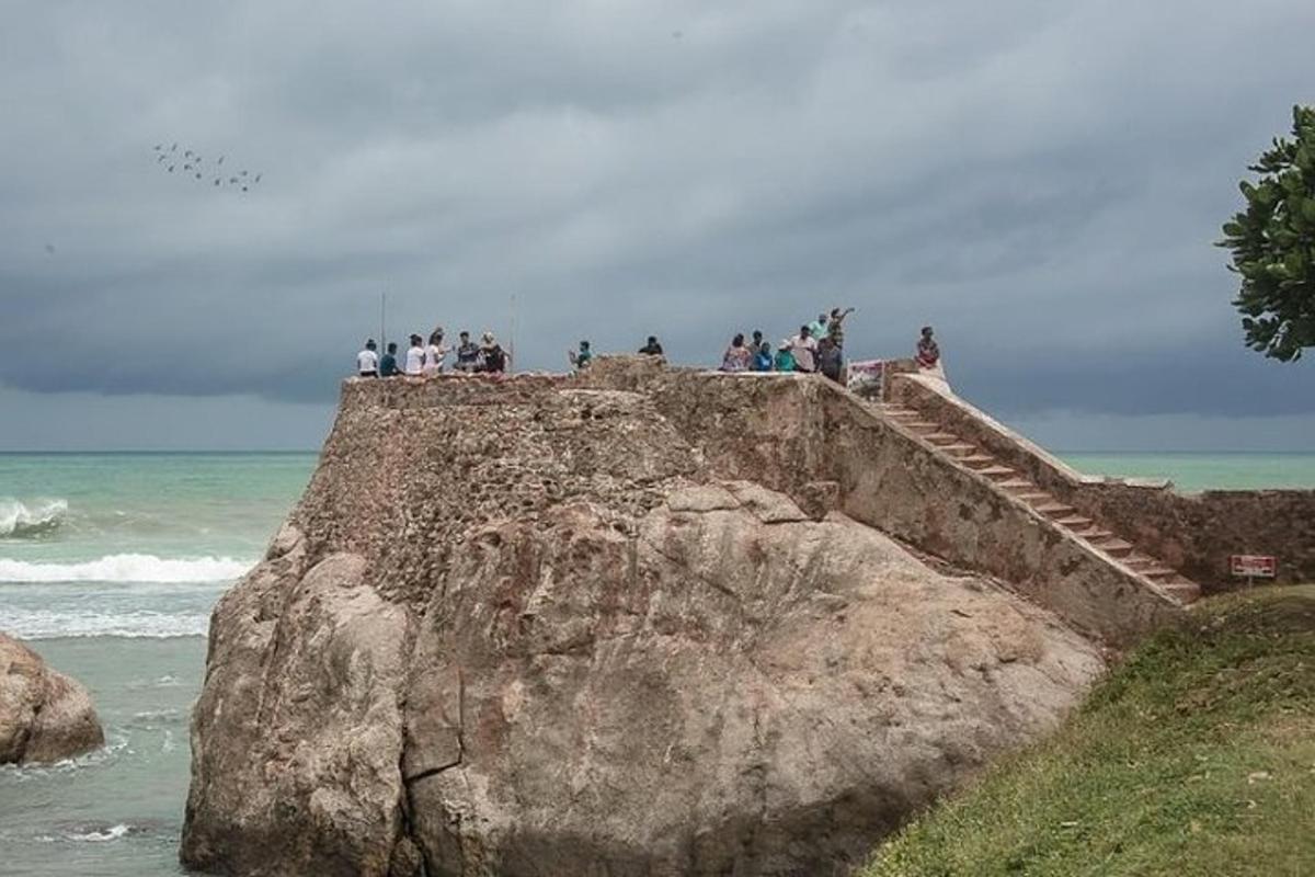 skupina lidí stojících na skále poblíž oceánu