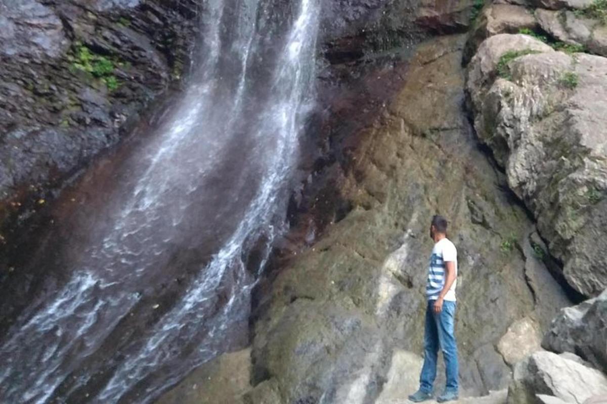 un uomo in piedi davanti a una cascata