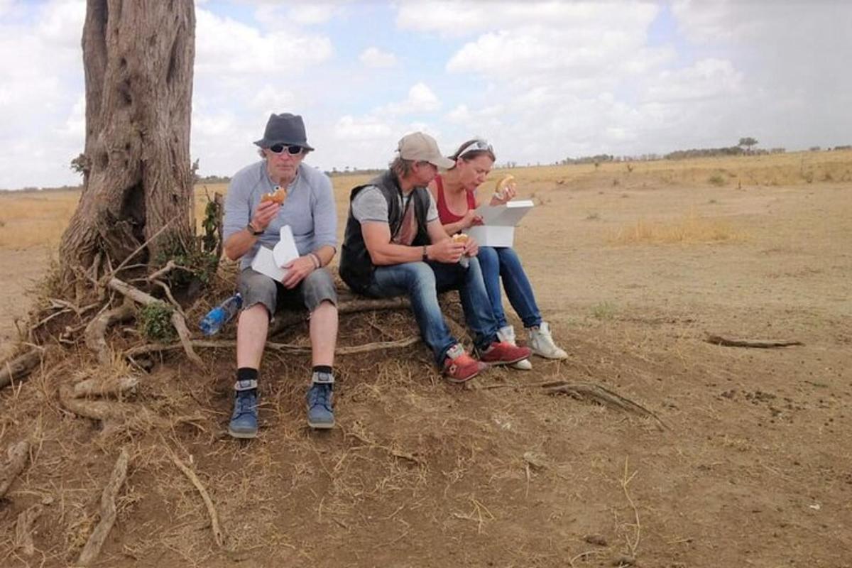 tre persone sedute accanto a un albero in un campo