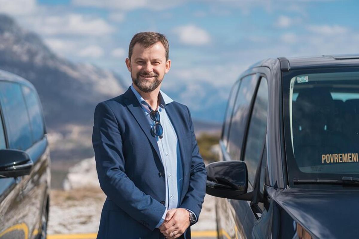 en mann i dress som står ved siden av en bil