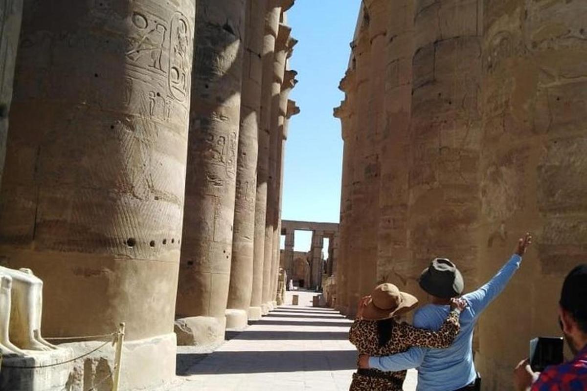 two people taking a picture of the ruins of the temple