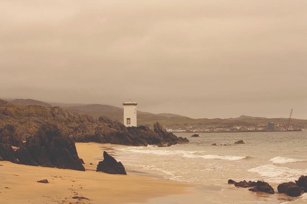 un faro sulla riva di una spiaggia con l'oceano