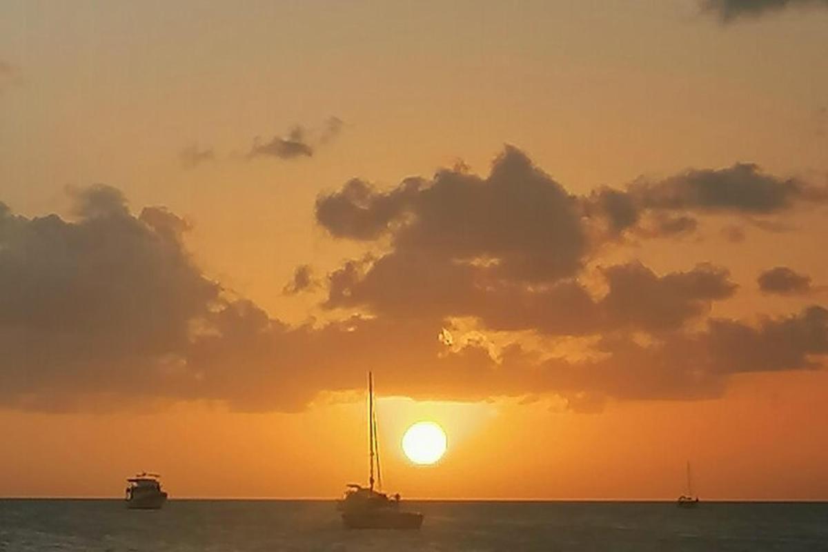 a sail boat in the ocean at sunset